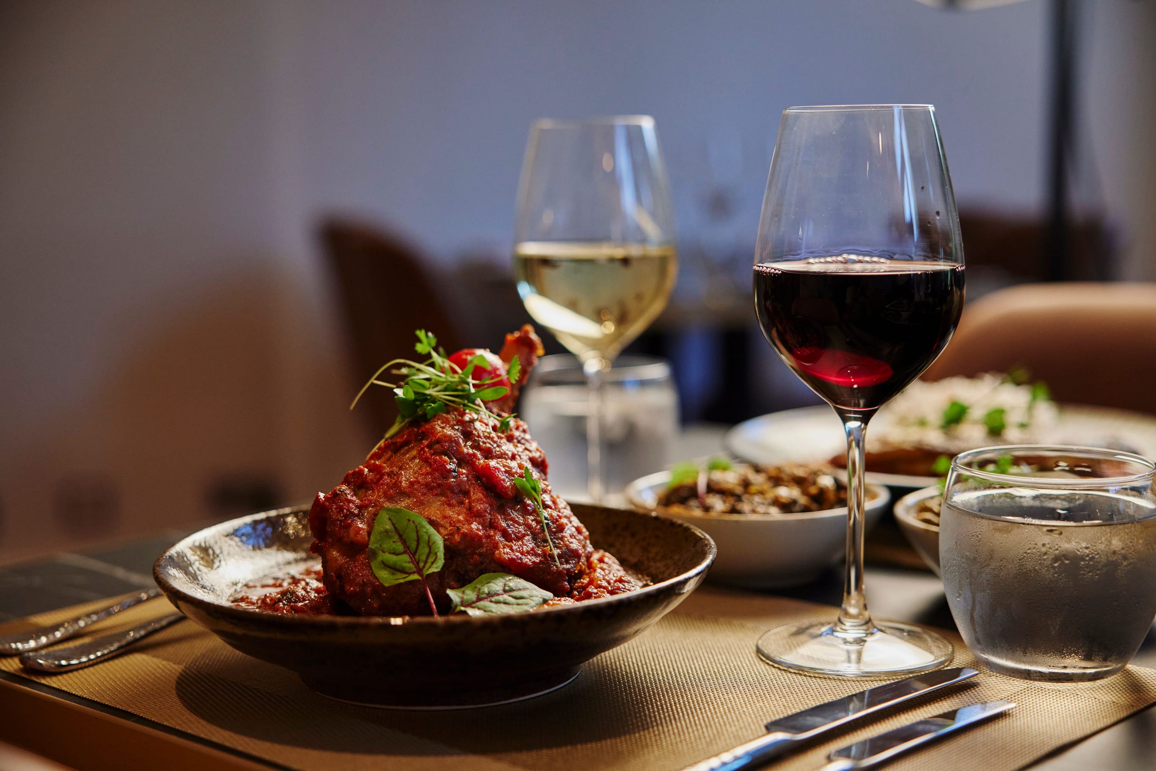 A spiced lamb dish with red and white wine at a candlelit SONA table