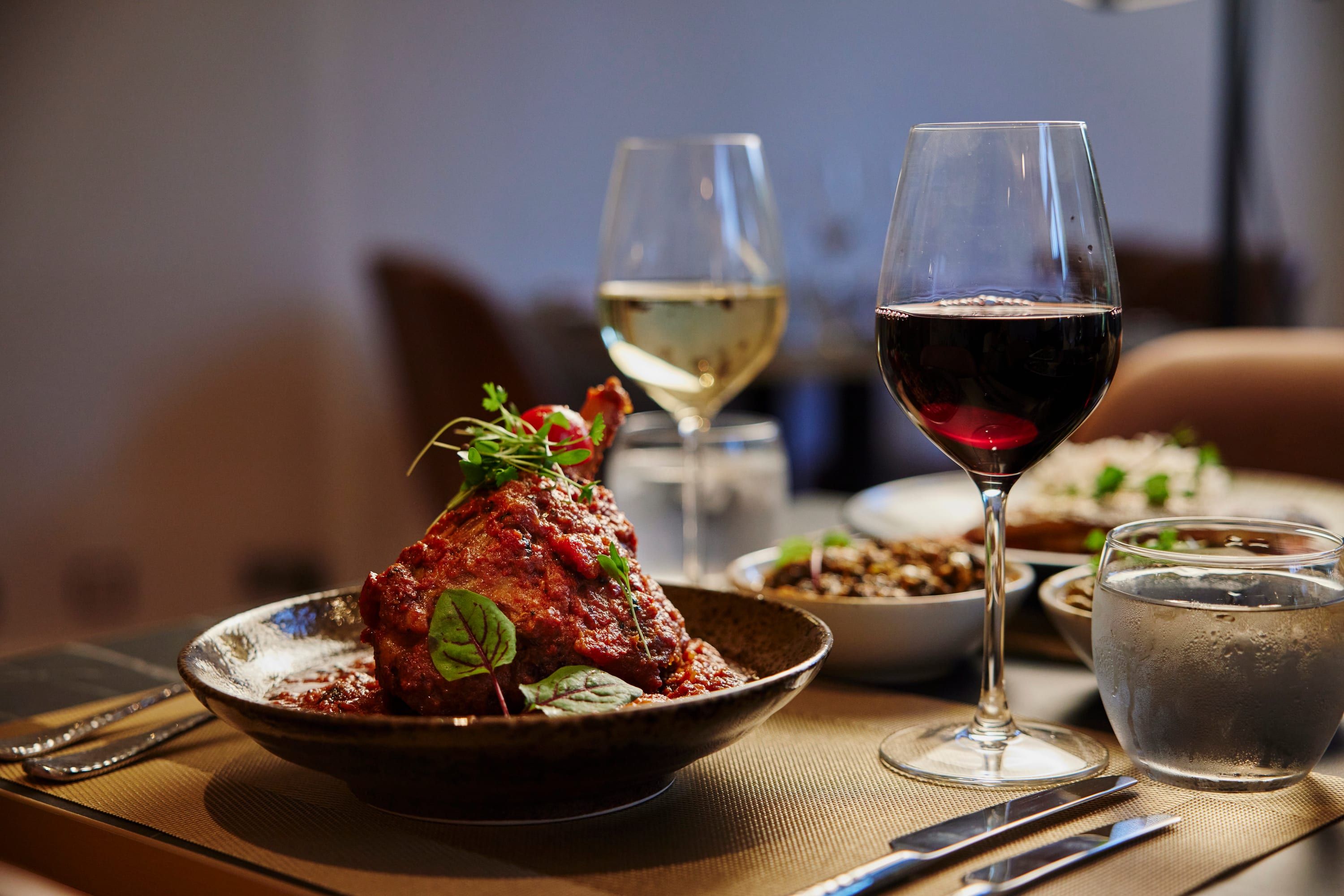 A spiced lamb dish with red and white wine at a candlelit SONA table