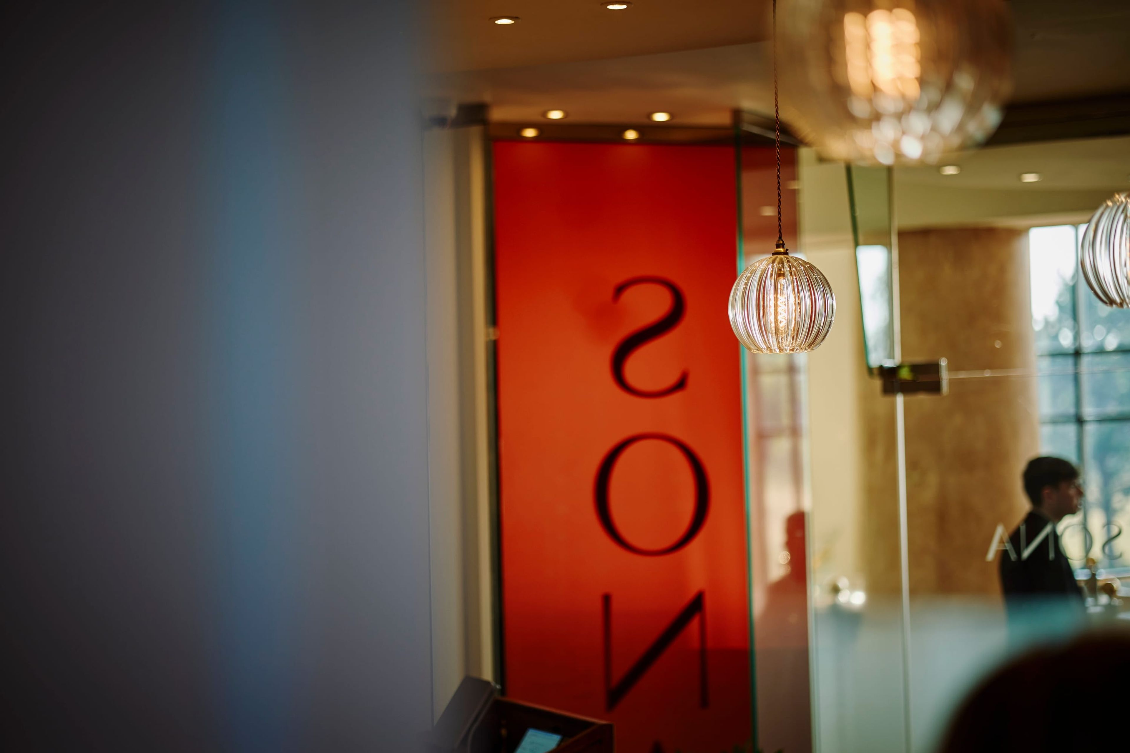 The illuminated SONA sign in the restaurant, with glass pendant lights