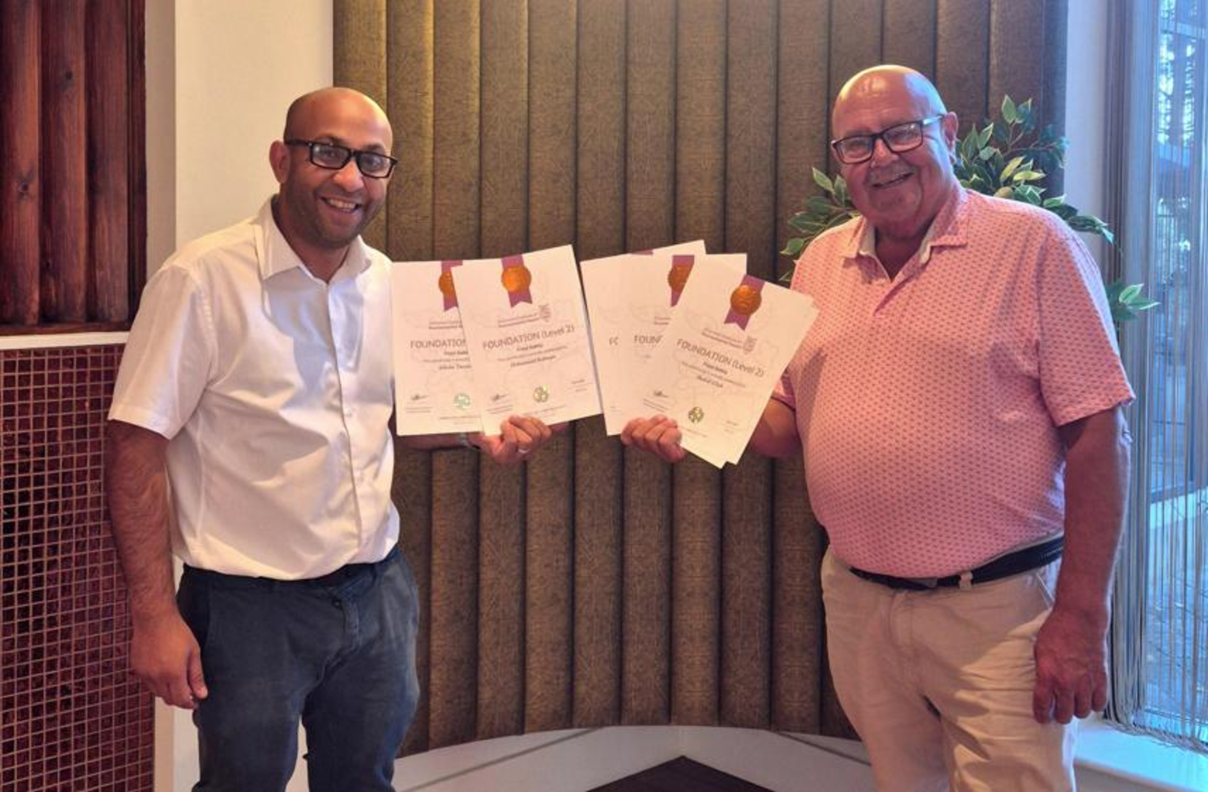 Faisal Rahman of SONA, left, smiling with Level 2 Food Safety certificates
