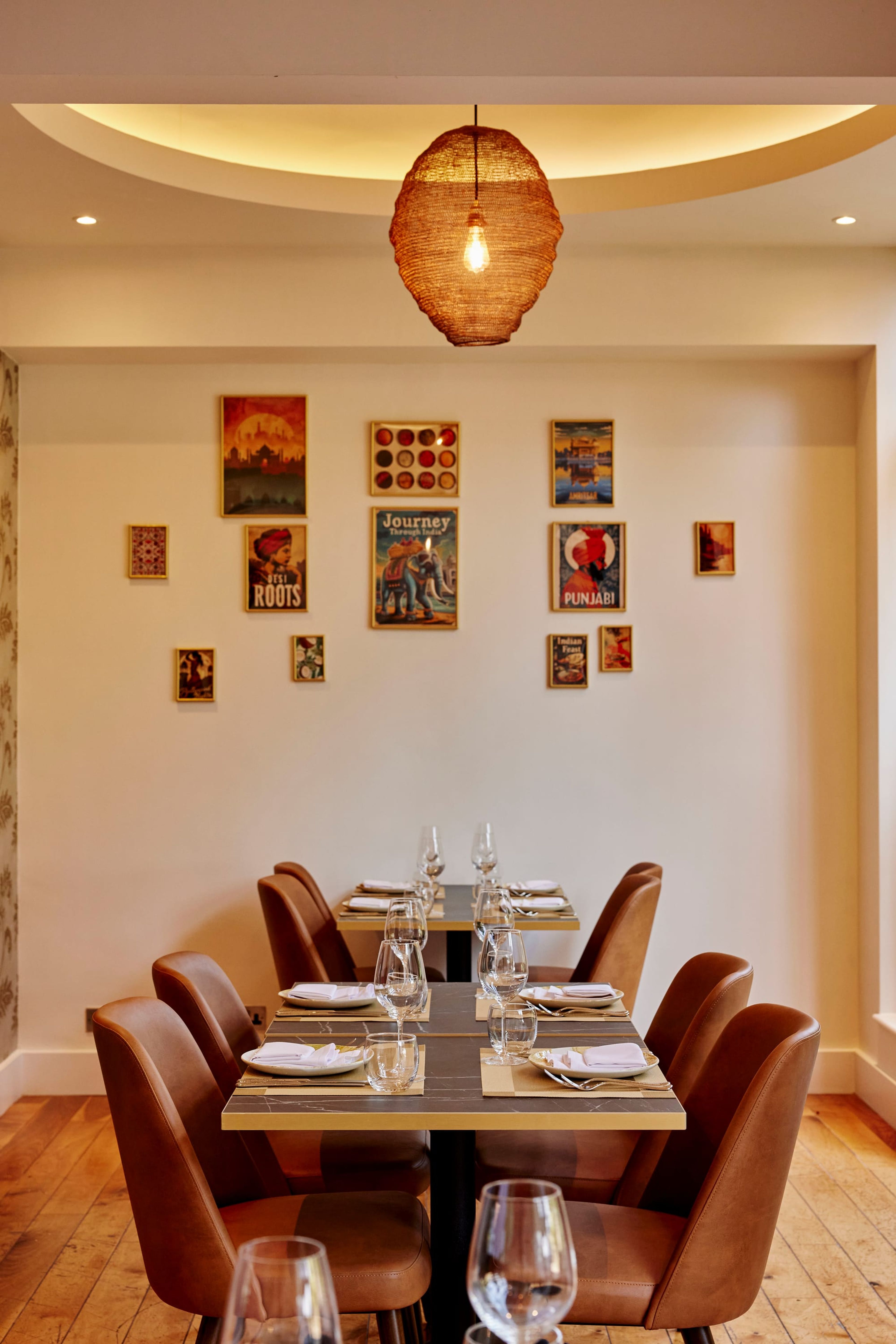 The private dining room at SONA, with a long table laid for a party beneath framed Indian prints