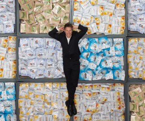 Ben Crowley lying on tubs of protein supplement products