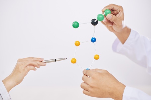 Scientists pointing at a specific molecule in a chemical structure.