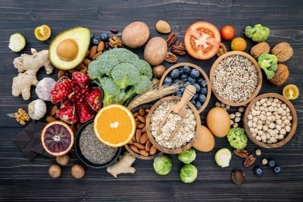 A mix of fruits, vegetables, grains, and nuts on a dark wood table.