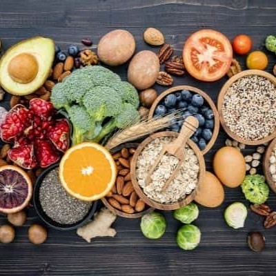 A mix of fruits, vegetables, grains, and nuts on a dark wood table.