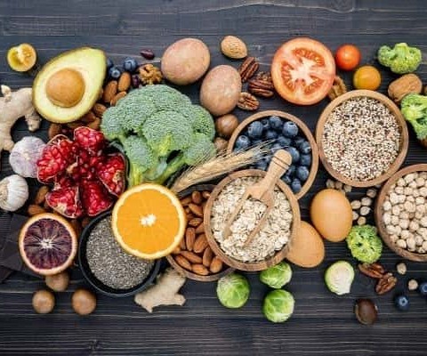 A mix of fruits, vegetables, grains, and nuts on a dark wood table.