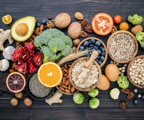 A mix of fruits, vegetables, grains, and nuts on a dark wood table.