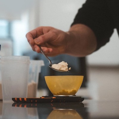 Person adding protein powder to a bowl for lab testing at Bulk Nutrients