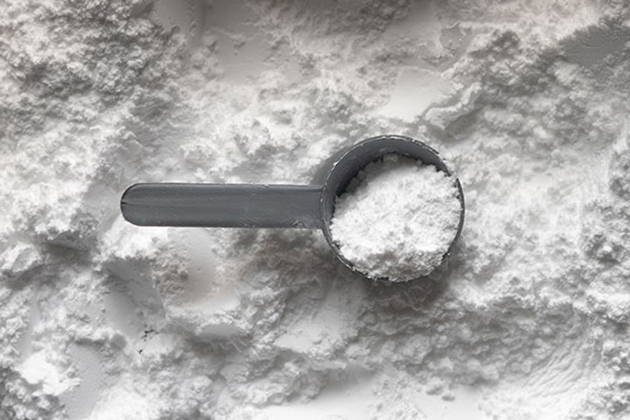 A scoop of creatine powder with a measuring spoon, highlighting its purity and benefits for strength, endurance, and muscle recovery.