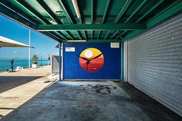 A silhouette of a bird flying past a sunrise painted on a roller door at a pristine beach in Darwin, Northern Territory.