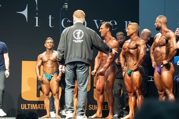 Former 7 time Mr. Olympia winner Arnold Schwarzenegger on stage with contestants.