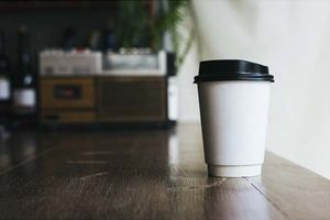 A disposable cup of coffee placed on a table. 