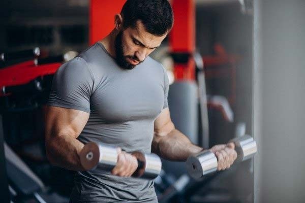 A muscular man performing bicep curls in the gym.