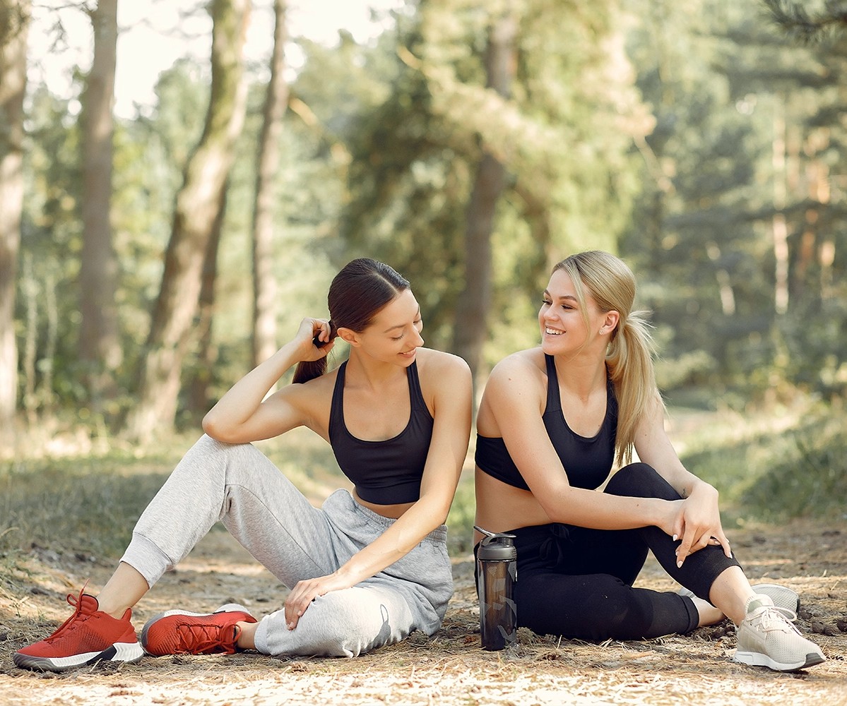 Two women sitting on a path after doing some exercise