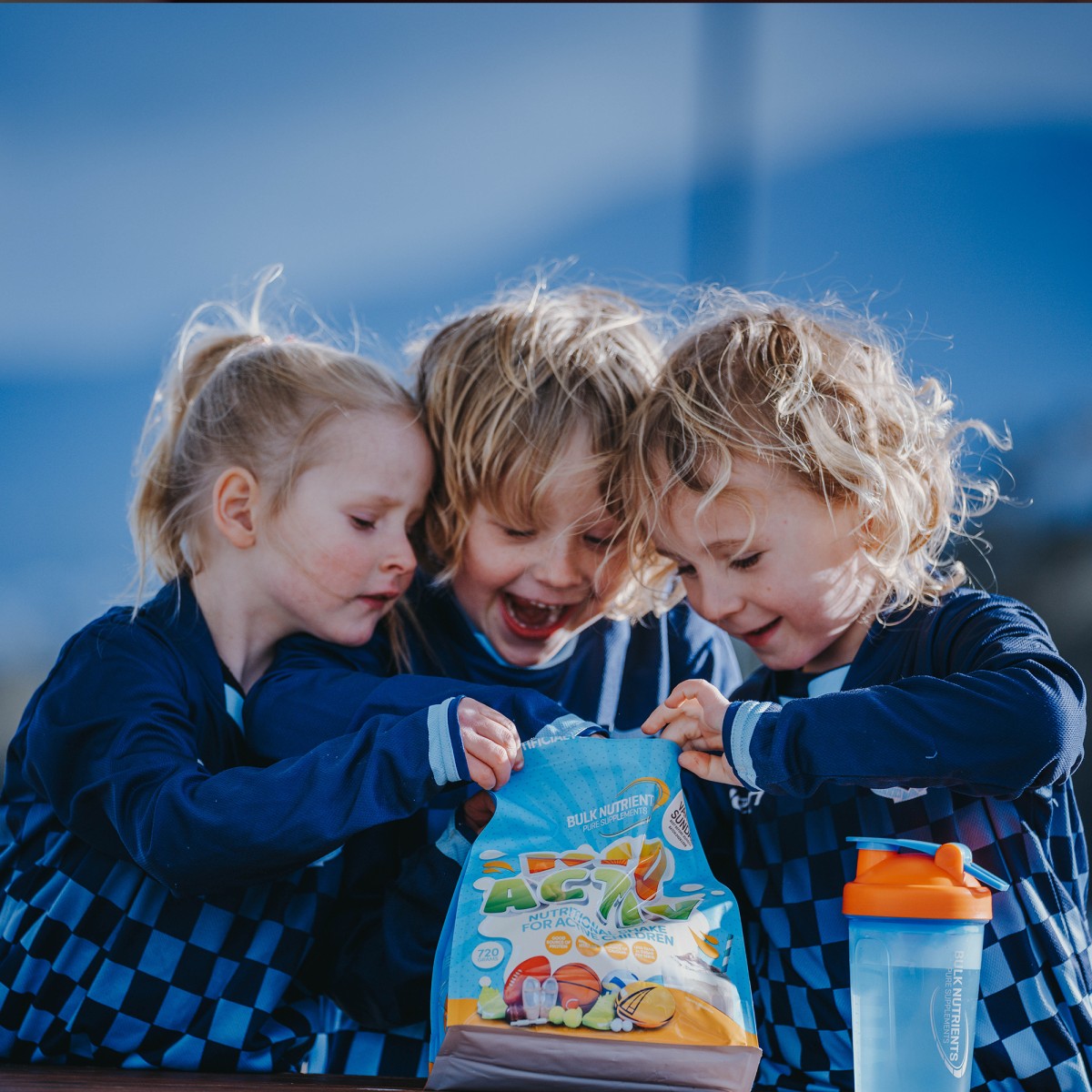 Three kids looking inside a bag of Bulk Nutrients KidActiv