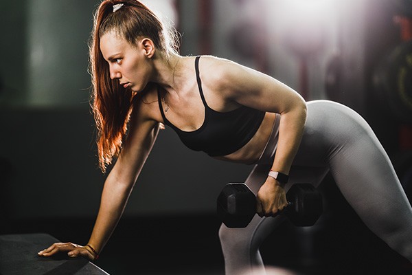 Woman working out hard at the gym with heavy weight