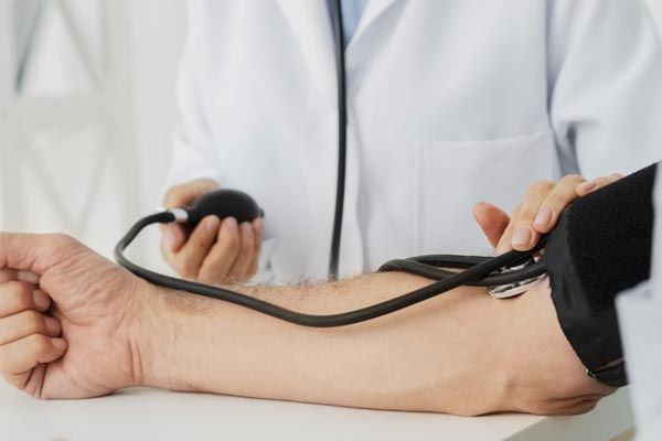 A man at the doctors having his blood pressure measure using a sphygmomanometer.
