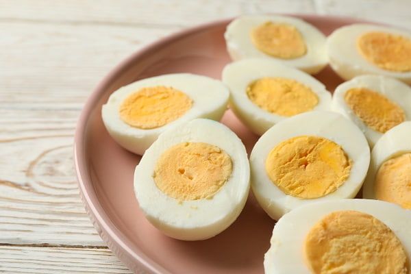 A half cut, hard boiled eggs on a light brown plate.