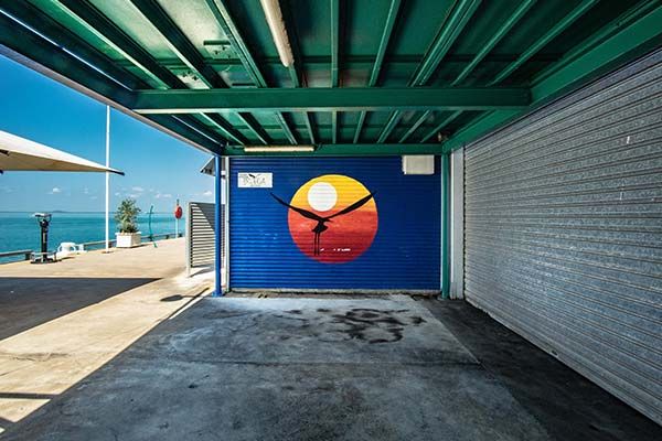 A silhouette of a bird flying past a sunrise painted on a roller door at a pristine beach in Darwin, Northern Territory. 
