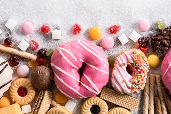 A bounty of sweet, sugar-filled confectioneries like donuts, biscuits, lollies, and chocolates.