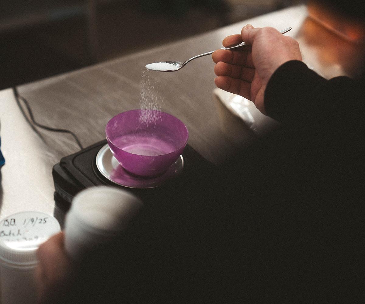 Person adding powdered supplement to a bowl on a digital scale