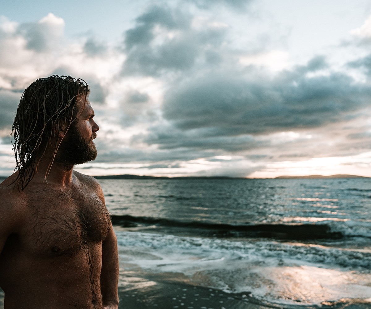 Man on the Beach with the water and land in the distance
