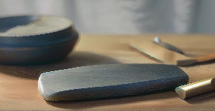 Close-up of a sharp carving tool on a sharpening stone, with a honing guide and honing compound in the background.