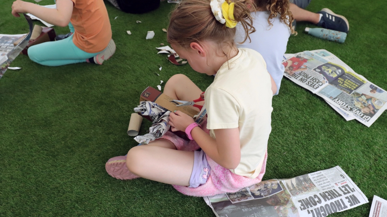 A child building an enrichment toy for a corvid out of cardboard and newspaper