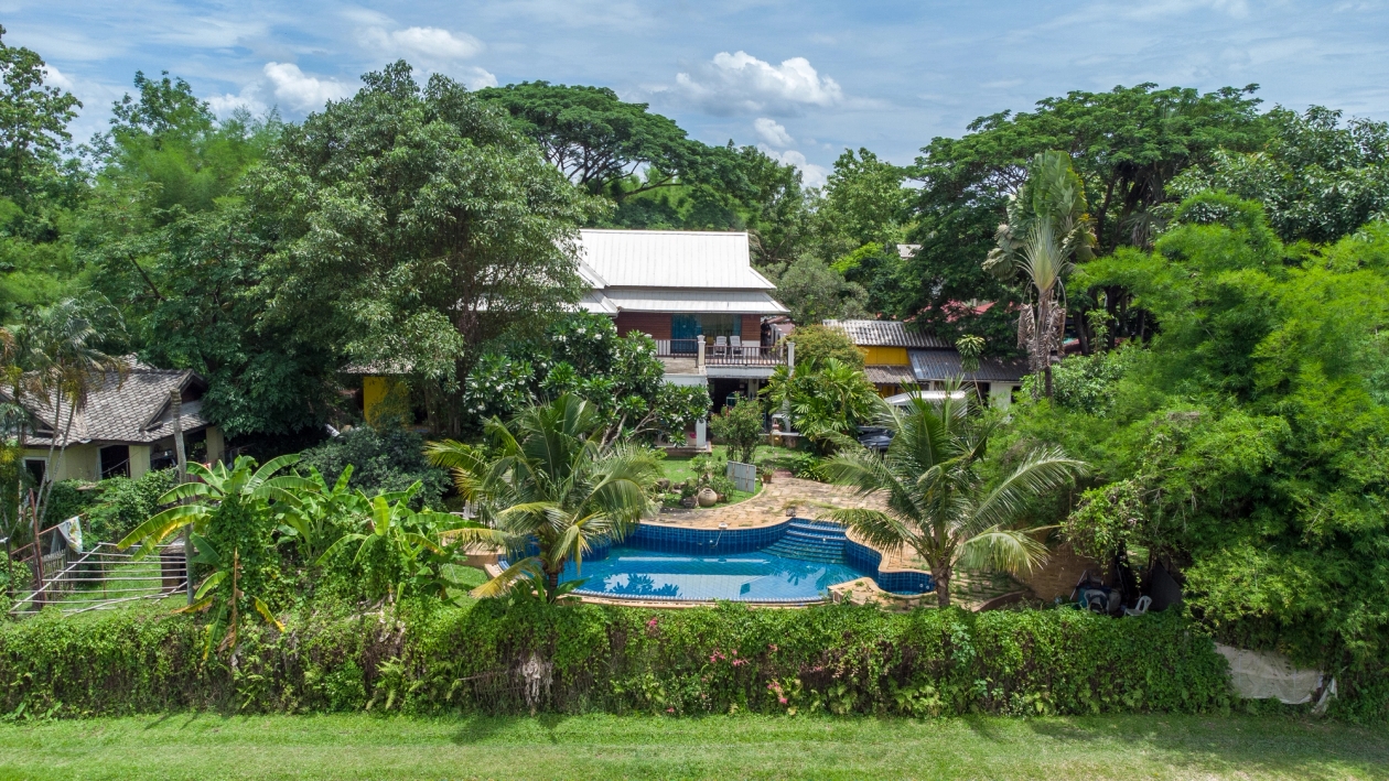 The Thailand International Training centre, a two story building surrounded by trees with a pool in front of it