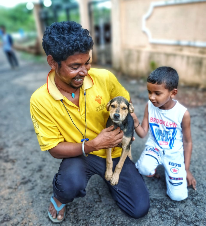 A dog and a child with a member of the Mission Rabies team