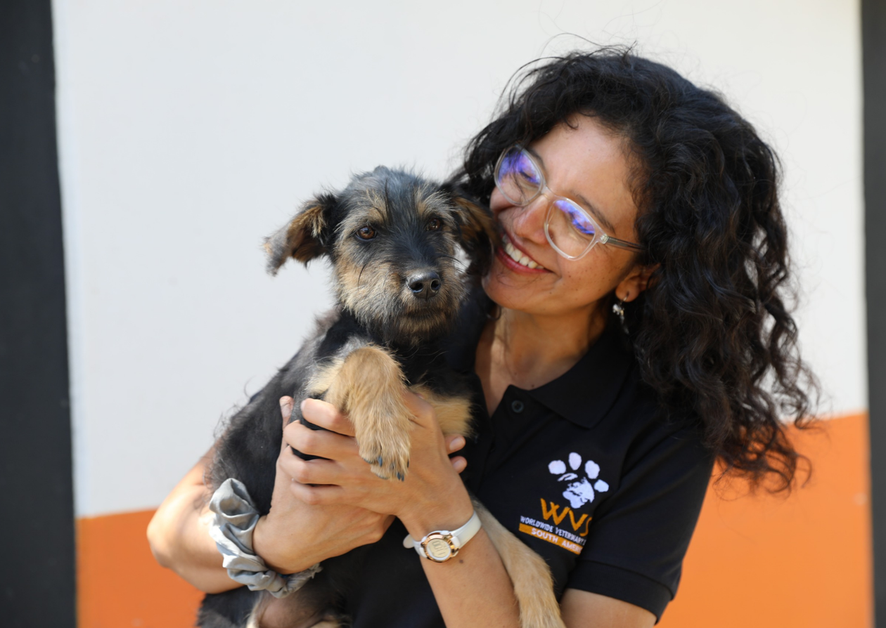 A women holding and smiling at a dog.