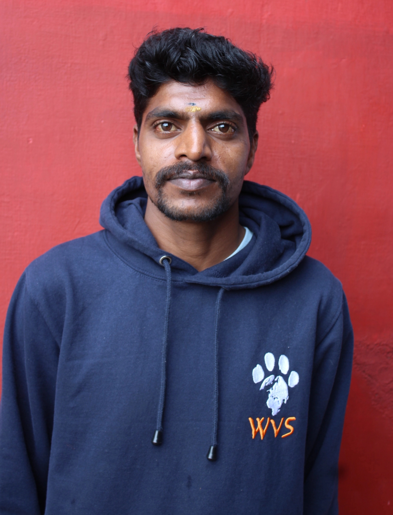 An Indian man wearing a WVS hoodie
