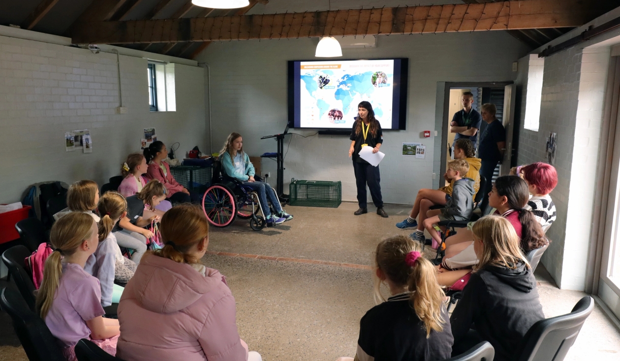 A group of children sitting a circle listening to Tigan talk about WVS's animal aid work