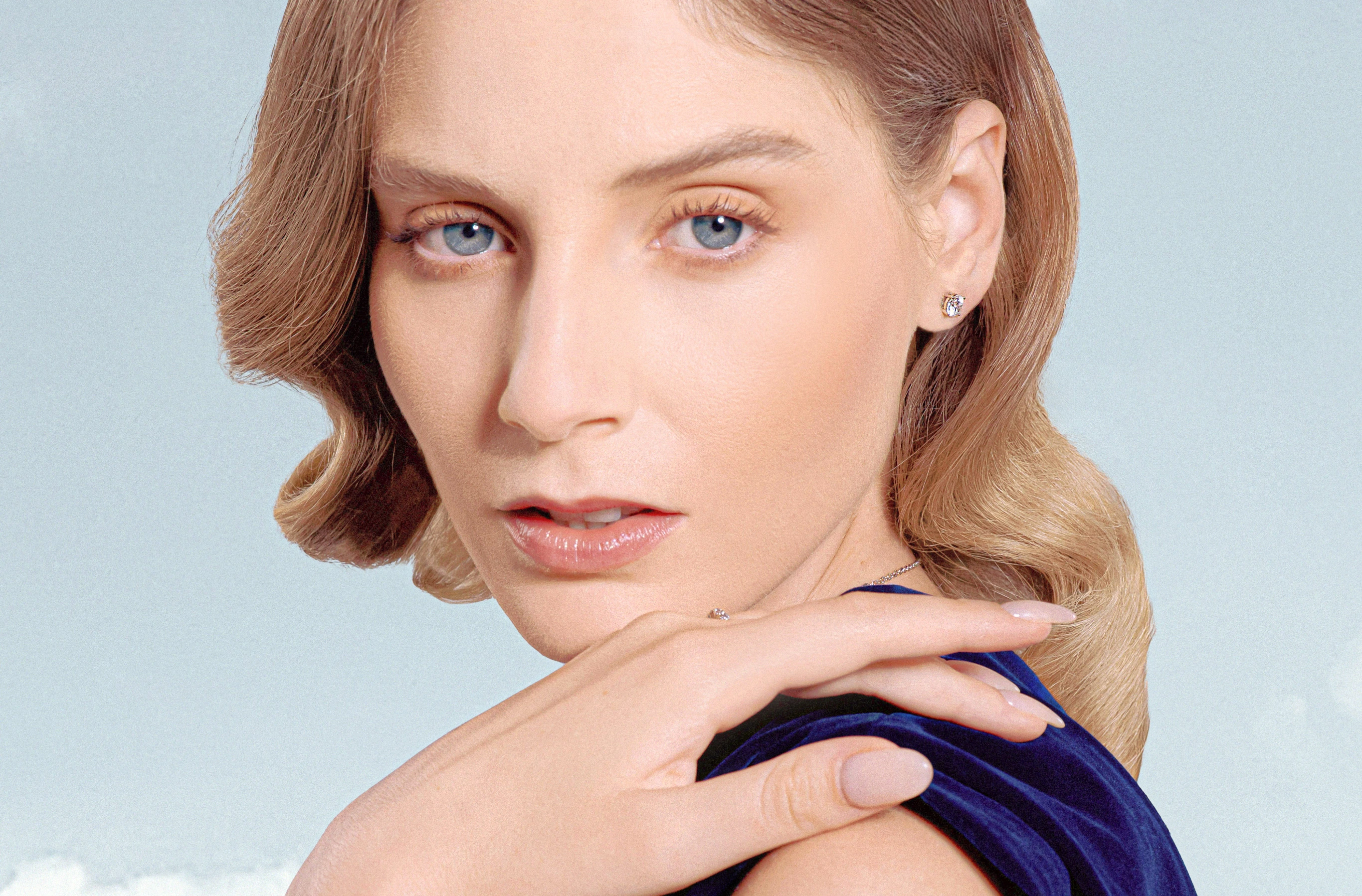 Woman in navy velvet wearing a diamond stud earring, looking toward the camera