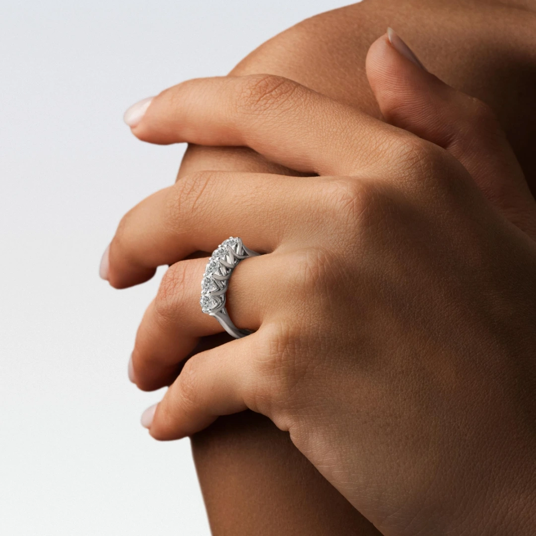 Hands wearing a white-gold three-stone diamond ring