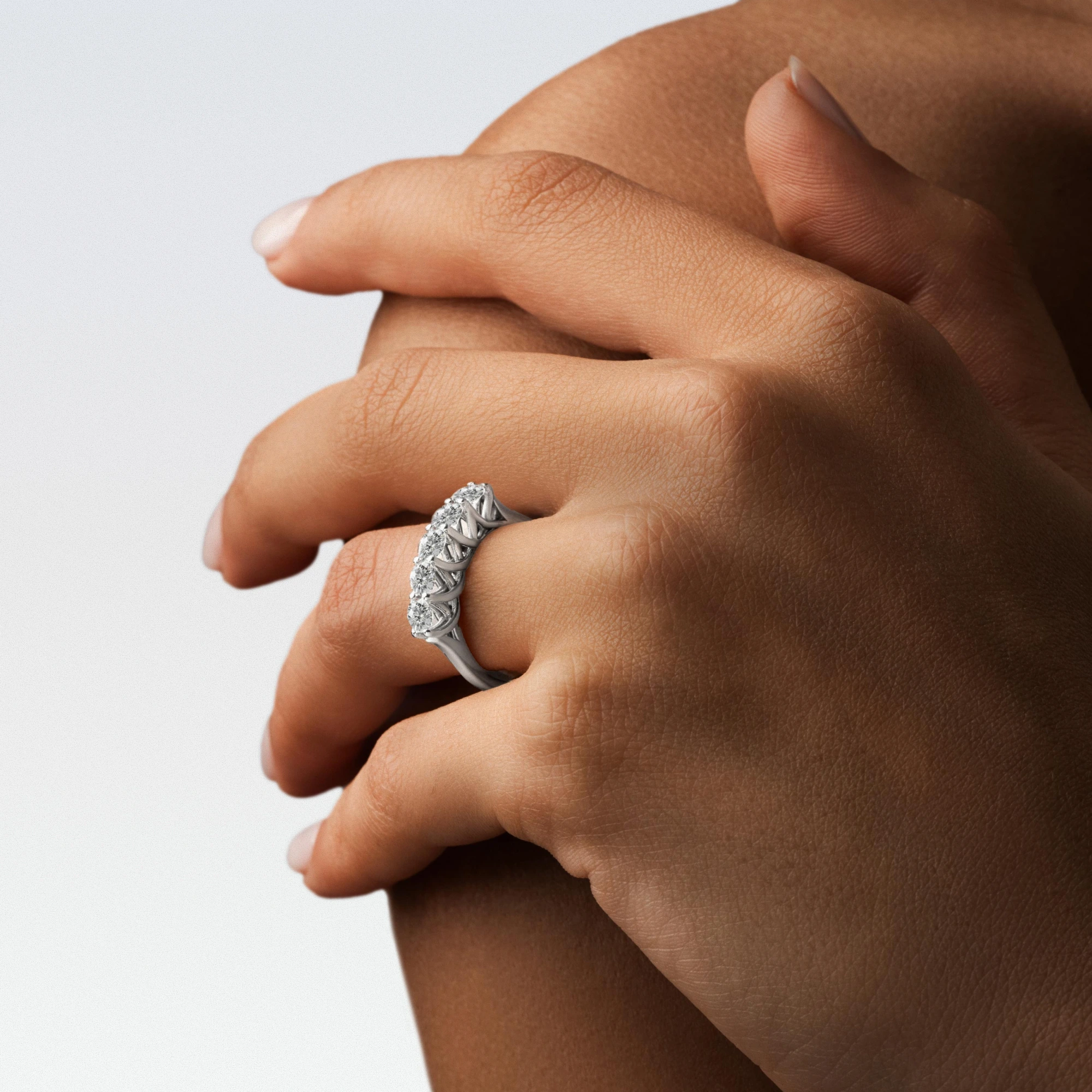 Hands wearing a white-gold three-stone diamond ring