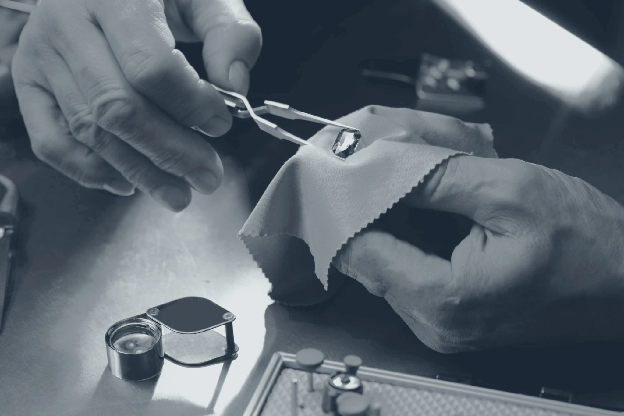 Gemologist examining a loose diamond with tweezers and a loupe