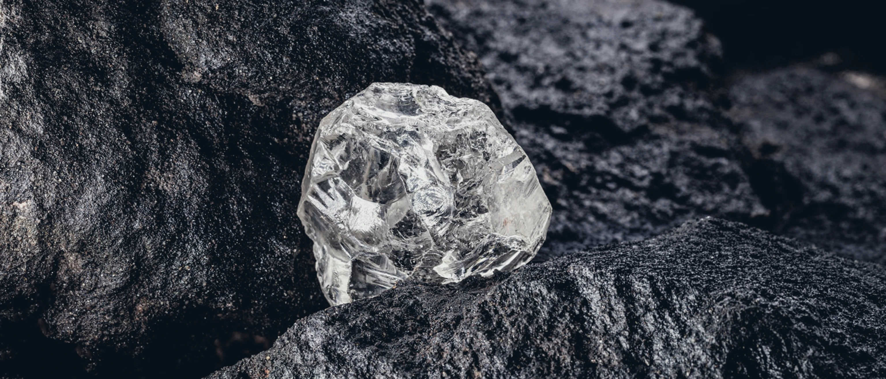 Natural rough diamond resting against dark rock
