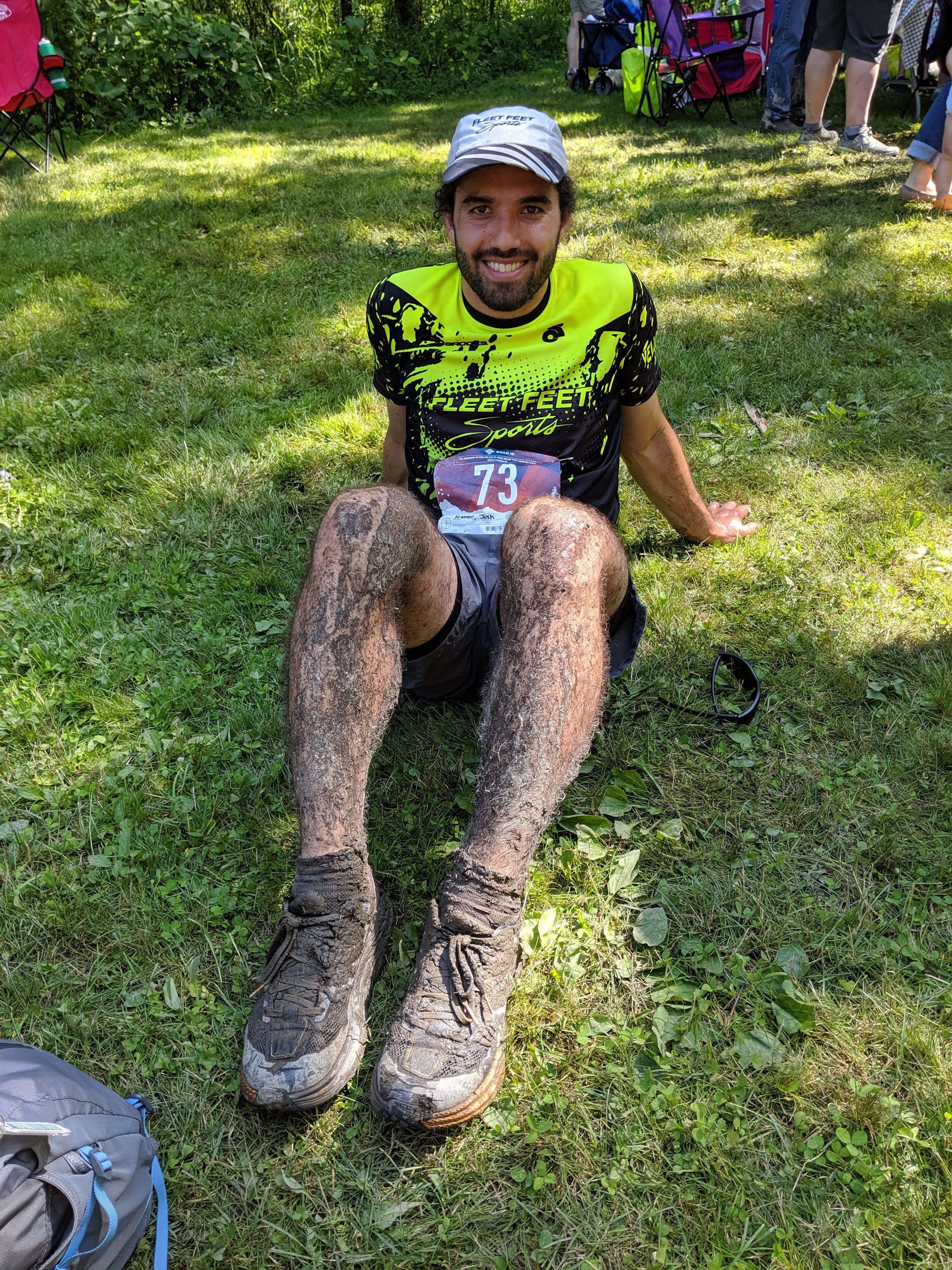 Me sitting down in the grass after finishing, with extremely muddy legs