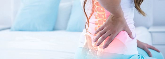 A woman clutching their lower back in pain