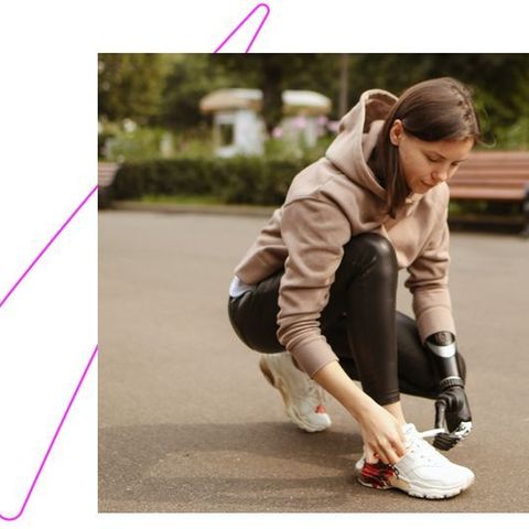 Mujer joven con un brazo robótico atándose los cordones de sus zapatillas