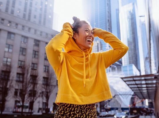 Mujer feliz con buzo con capucha amarilla, la ciencia para saber qué es el sudor