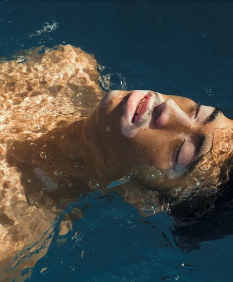 Un hombre en una piscina con el sol brillando en su cara