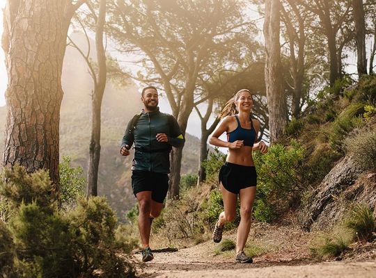 Couple running on a forest trail. 