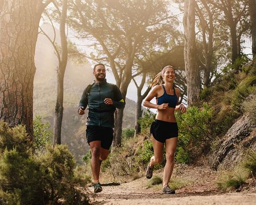 Couple jogging on a forest trail. 