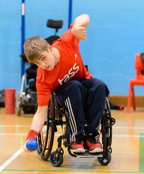 A man in a wheelchair, bowling a blue ball