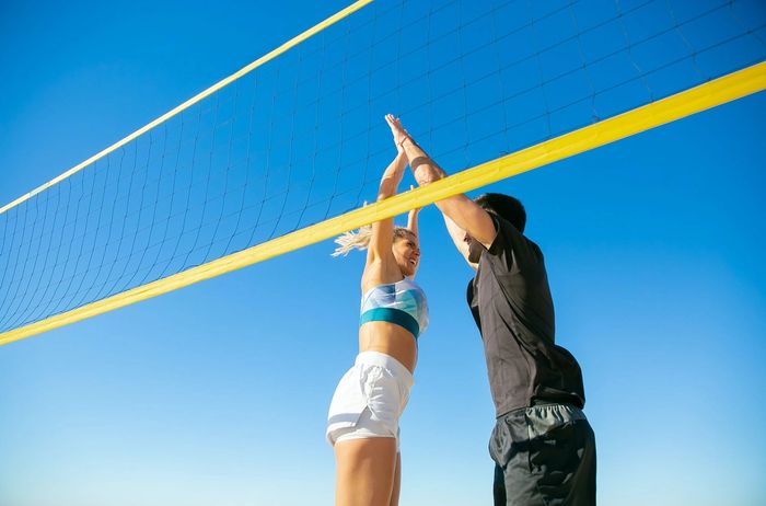 man and woman high fiving playing volleyball
