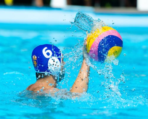 Man in pool in waterpolo gear about to throw ball