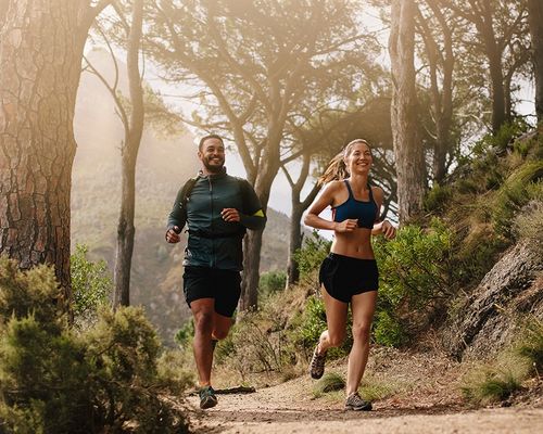 Couple jogging on a forest trail. 