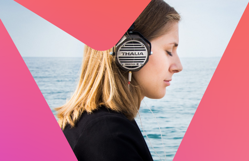 Woman with eye closed listening to headphones in front of the sea